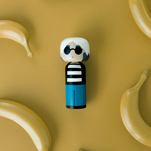 Sketch Inc. for Lucie Kaas modern wooden kokeshi doll as Andy Warhol shown against a yellow banana background